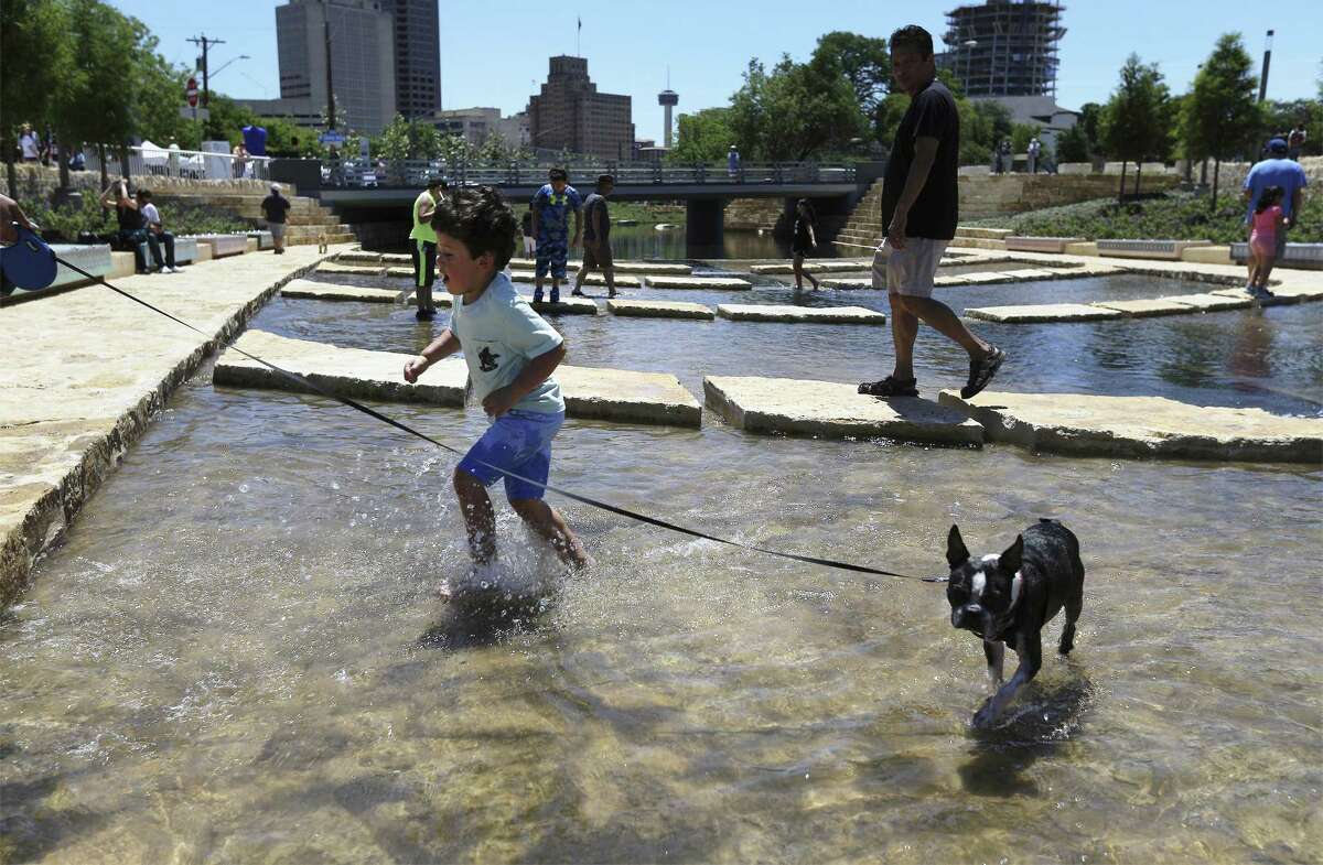 A youngster splashes in the water beside his dog at San Pedro Creek Culture Park in San Antonio. A reader says it makes no sense to allow people to wade in the water, risking the threat of bacterial infection.