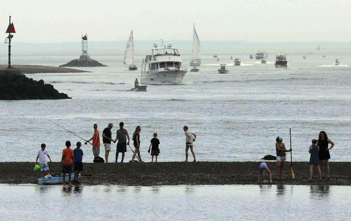 Beachgoers watch the boats in Norwalk Harbor as they visit Calf Pasture Beach for the Memorial Day weekend Saturday, May 26, 2018, in Norwalk, Conn.