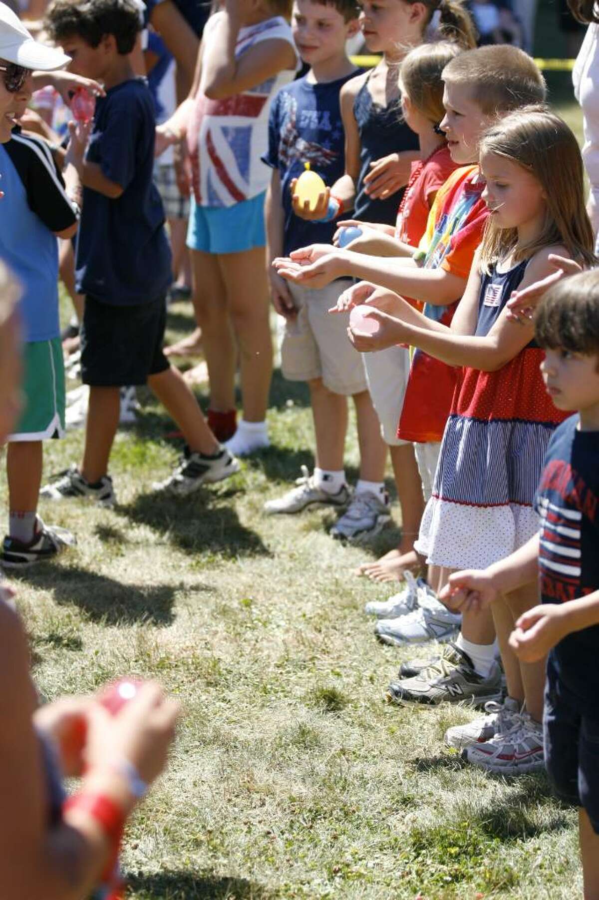 Children line up to compete in a water-balloon toss during the Pequot Library's Independence Day festivities in Southport on Sunday, July 4, 2010.