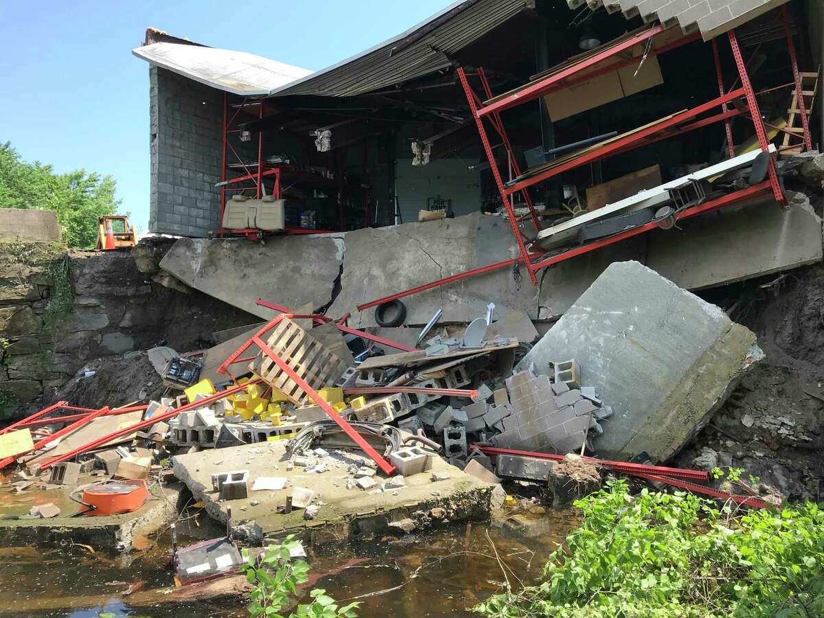 A storage garage attached to the rear of Abacore Electric, a factory building at 281 Canal Street in Shelton, Conn. fell, spilling its contents into the Housatonic River on Tuesday, May 29, 2018.