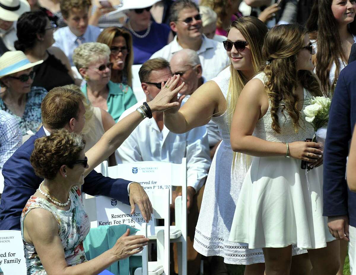 Carol Carmody, left, a parent and trustee of Canterbury School, high-fives graduate Jenna Tressa during the processional into commencement exercises on Friday.
