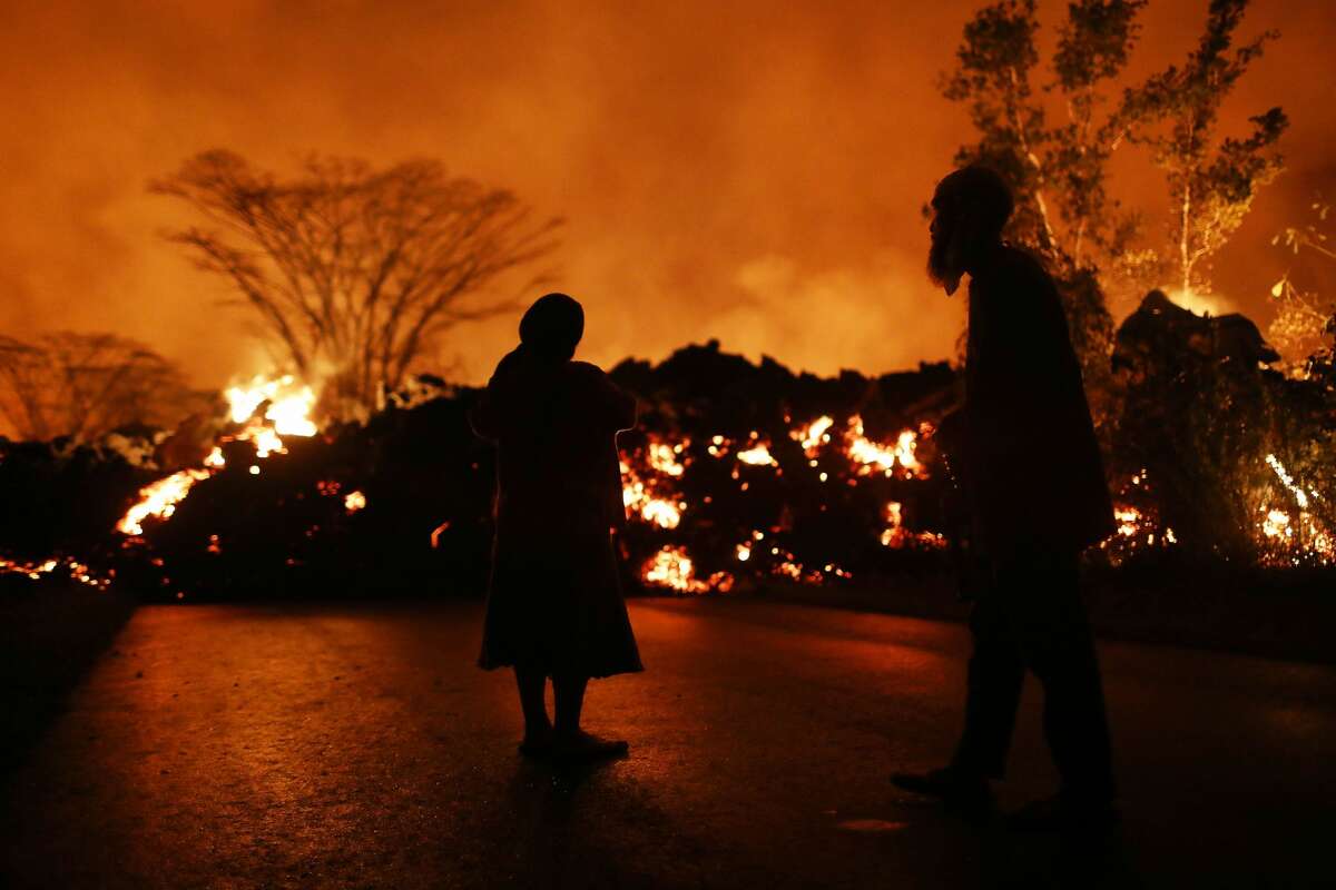 Residents watch as lava from a Kilauea volcano fissure advances on a roadway in Leilani Estates, on Hawaii's Big Island, on May 25, 2018 in Pahoa, Hawaii. Following a magnitude 4.4 earthquake today centered in the summit region of the Kilauea volcano, an ash plume was sent from the volcano at least 10,000 feet skyward, according to the National Weather Service.