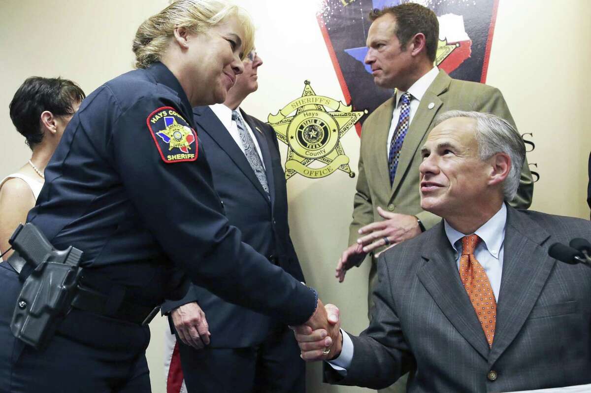 Gov. Gregg Abbott shakes hands with the Hays County Sheriff's Lt. Jeri Skrocki whom he cited as he reveals his school safety proposals at a press conference at the Hays County Law Enforcement Center in San Marcos on May 30, 2018.