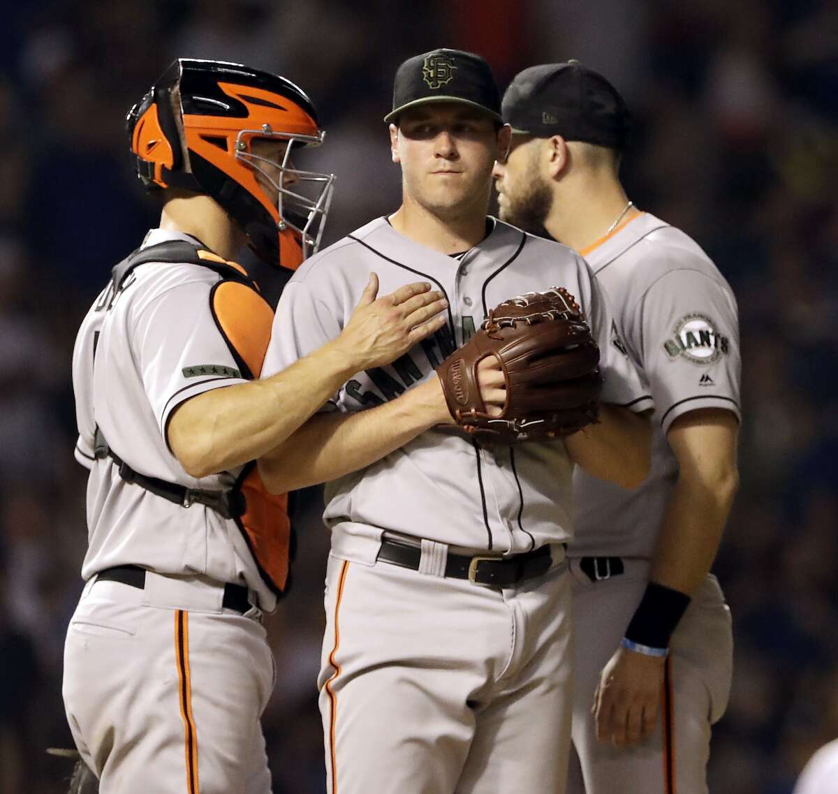 San Francisco Giants starting pitcher Ty Blach, center, reacts as he listens to catcher Nick Hundley, left, and third baseman Evan Longoria during the fourth inning of a baseball game against the Chicago Cubs in Chicago, Sunday, May 27, 2018. (AP Photo/Nam Y. Huh)