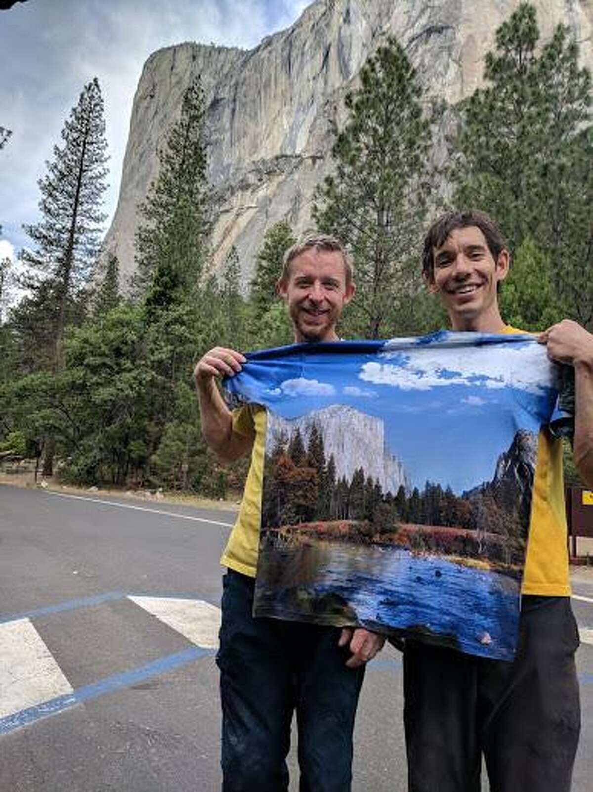 Tommy Caldwell and Alex Honnold hold a t-shirt with an image of the mountain they just climbed as they celebrate their record on the Nose route of El Capitan.