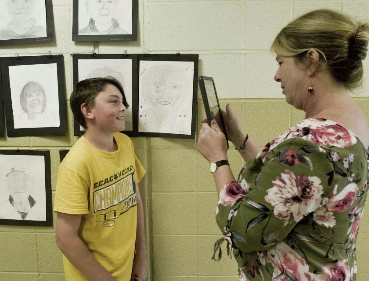 Scotts Ridge Middle School seventh-grader Henry Idone stands with the portrait he drew of a Founders Hall member as school library assistant Emily Shiller gets a picture. Portraits are displayed on the school hallway walls. Wednesday, May 30, 2018