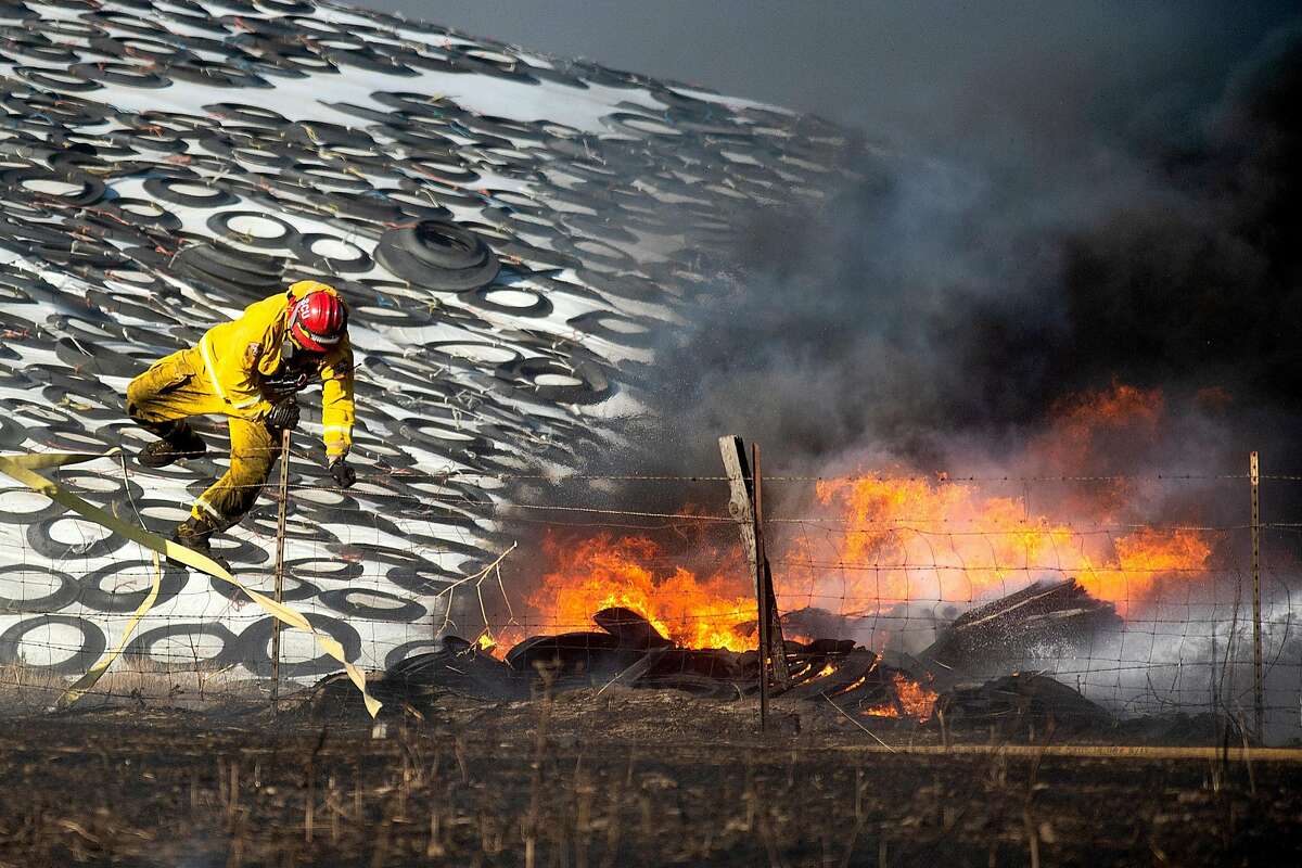 A firefighter scales a fence while battling one several blazes near Altamont Pass on Wednesday, May 30, 2018, in Byron, Calif.