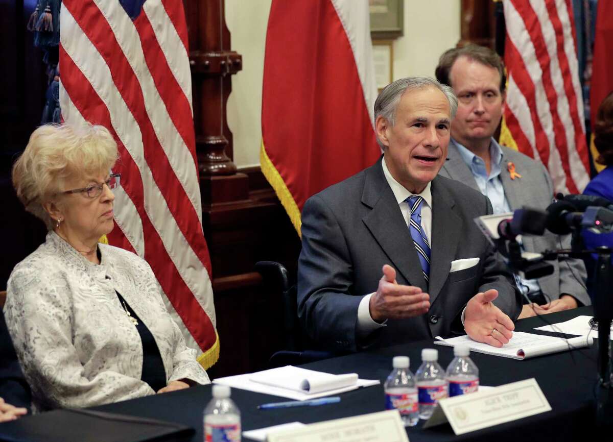 Texas Gov. Gregg Abbott is flanked by Alice Tripp of the Texas State Rifle Association, left, and Ed Scruggs, board vice-chair of Texas Gun Sense, during a roundtable discussion to address safety and security at Texas schools in the wake of the shooting at Santa Fe on May 23, 2018.
