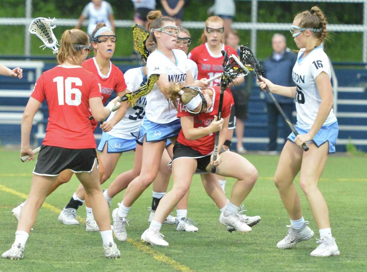 New Canaan's #14 Campbell Connors gets the ball through defenders vs Wilton High School in girls lacrosse action on Thursday May 31, 2018 in Wilton Conn