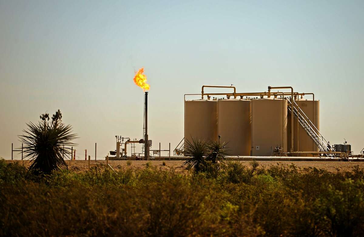 A natural gas flare is visible near storage tanks May 30, 2018, in Reeves County, Texas. Global demand for natural gas fell 2.5 percent in 2020, despite the economic lockdowns caused by the coronavirus pandemic, according to a new report.