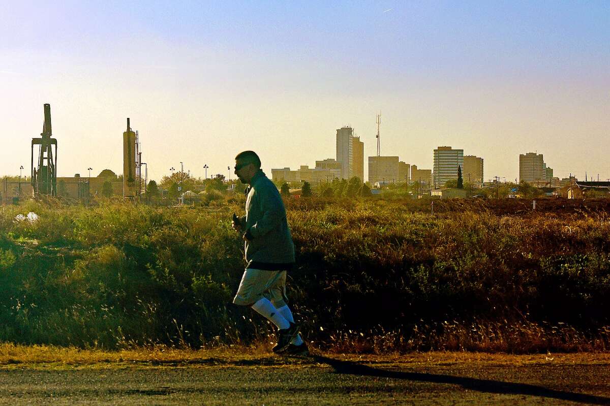 A jogger travels along Fairgrounds Road past a pumpjack and the downtown skyline on Nov. 21, 2017. James Durbin/Reporter-Telegram