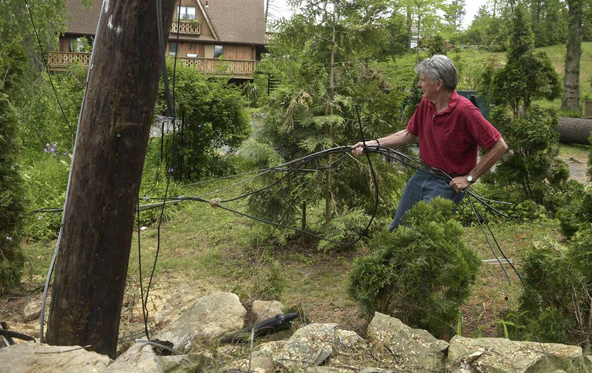 Robert Steinberg cleans up cut wires that remain on his property on Forty Acre Mountain Road, on Thursday, May 31, 2018, in Danbury, Conn.