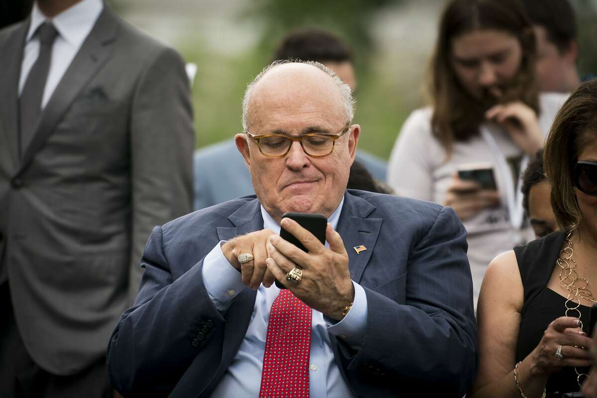 Rudy Giuliani checks his phone at an event at the White House in Washington, May 30, 2018.