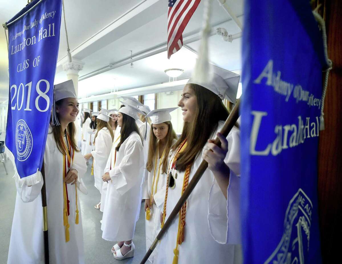 Milford, Connecticut - June 2, 2018: Lauralton Hall Salutatorian Lily Wald of Derby, left, and Valedictorian Caroline Favano of Norwalk right, hold on to Lauralton Hall banners as the wait to lead the Lauralton Hall Class of 2018 Graduation processional Saturday at Lauralton Hall in Milford.