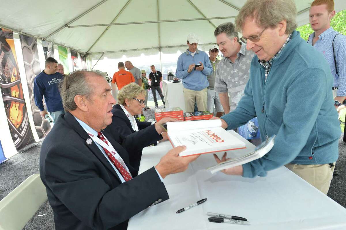 Race car driver and automotive expert David Hobbs signs a copy of his new book 'Hobo' his knickname, for Redding's Tom O'Keefe during the Greenwich Concours d'Elegance at Roger Sherman Baldwin Park in Greenwich Conn. on Sunday june 3, 2018