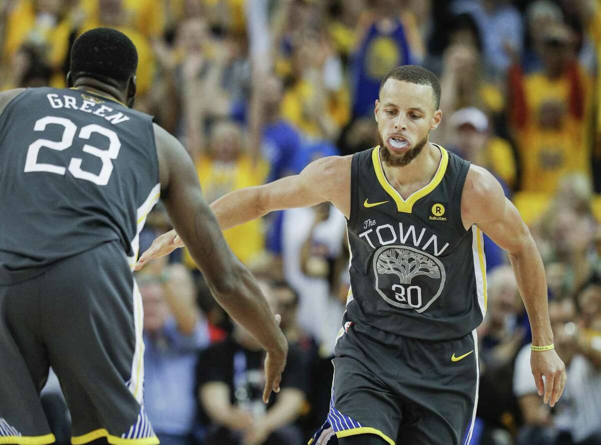 Golden State Warriors' Stephen Curry reaches for Draymond Green's hand in the fourth quarter after hitting a three-pointer during game 2 of The NBA Finals between the Golden State Warriors and the Cleveland Cavaliers at Oracle Arena on Sunday, June 3, 2018 in Oakland, Calif.