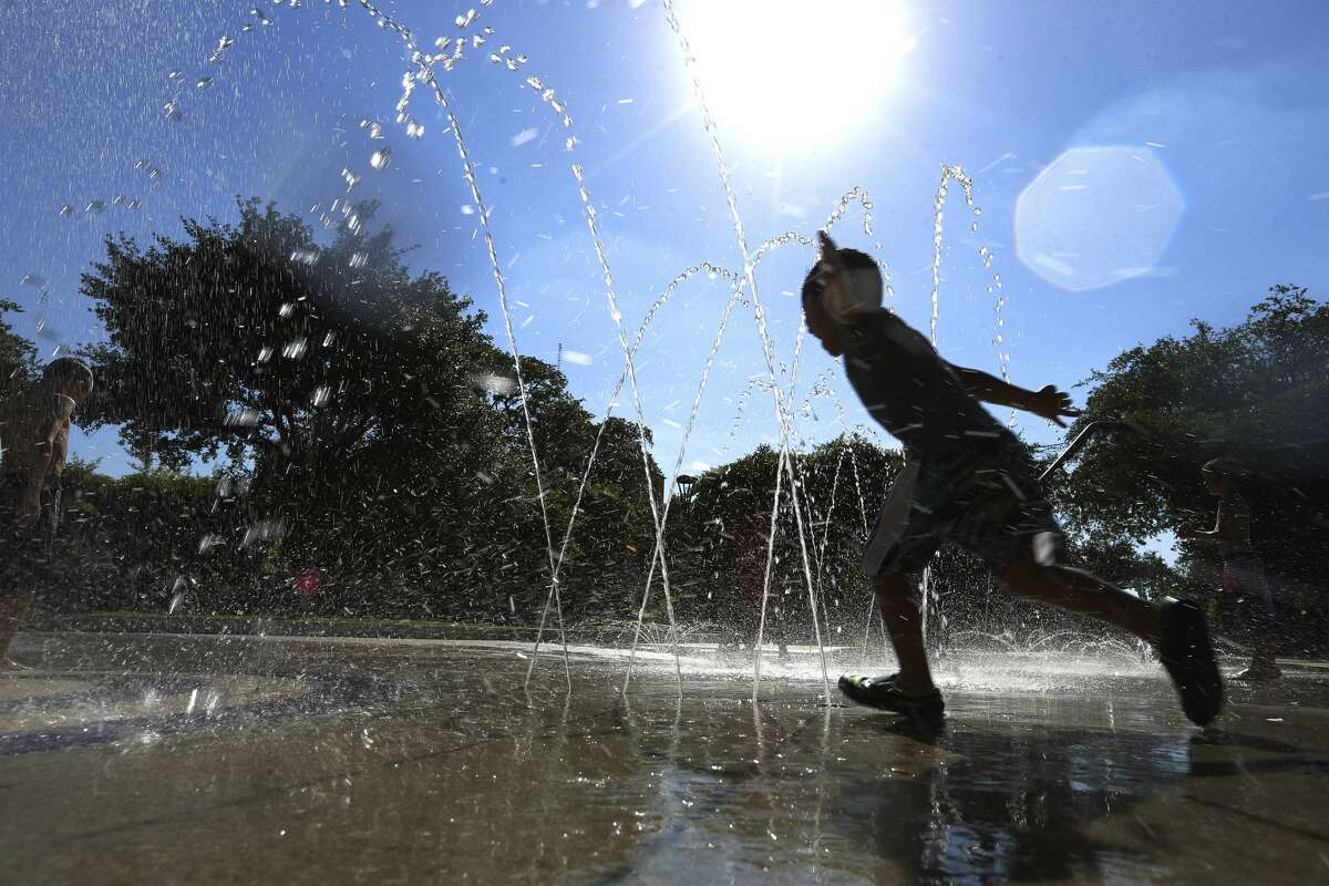 A young boy runs through a fountain of water at Yanaguana Garden and Playground near the Tower of Americas on Tuesday, May 29, 2018. A pattern of high temperatures reaching near or into the century mark has made many people seek relief from the heat. For some families, the park's fountain was ideal for cooling off. Tuesday's high was in the mid-90's. (Kin Man Hui/San Antonio Express-News)