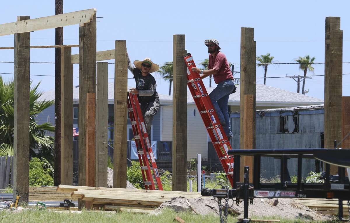 Construction workers climb ladders to secure wooden framing in Port Aransas on Saturday, May 26, 2018. San Antonio residents made the three-hour trek to Port Aransas to celebrate Memorial Day weekend. Since Hurricane Harvey struck the area last year, the city and business owners have been racing to recover from the devastating storm and draw tourists back to the tiny island town. City Mayor Charles R. Bujan said despite perfect conditions for the beaches and nearly all restaurants have reopened, accommodations for visitors is still only at about half of usual capacity. (Kin Man Hui/San Antonio Express-News)