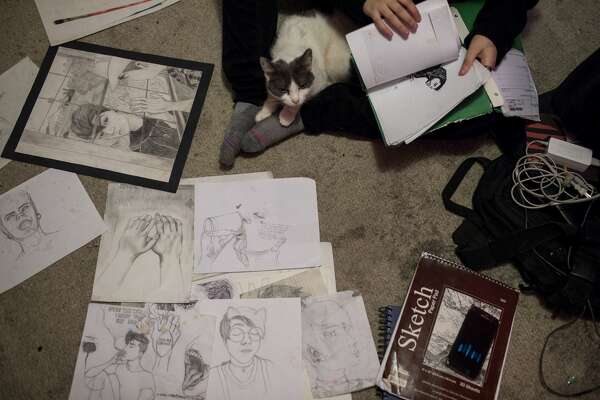 Dakota sits with his cat Pepper as he flips through his artwork. in one portrait, the version of him his family wants -- the female body of a girl named Shelby -- smiles through her makeup as she sees who she really wants to be: Dakota.