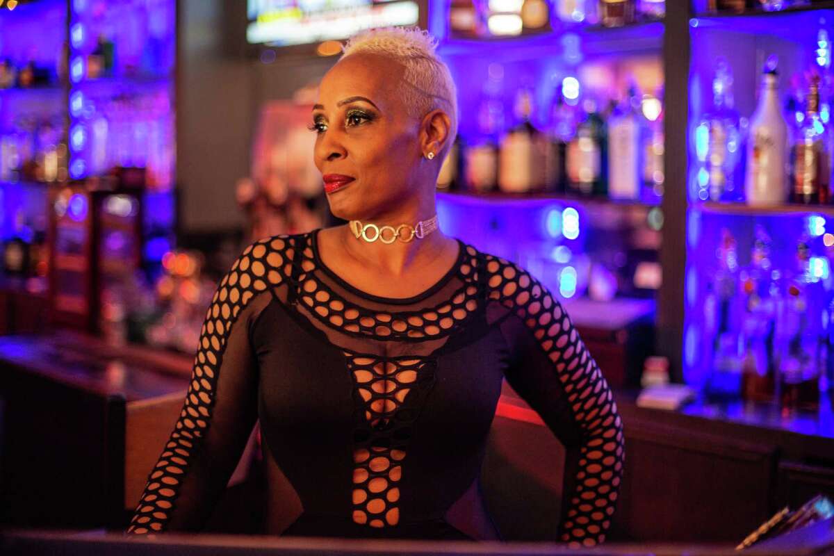 Dee Lewis, a bartender at Dreams Bar & Lounge poses for a portrait behind the bar.