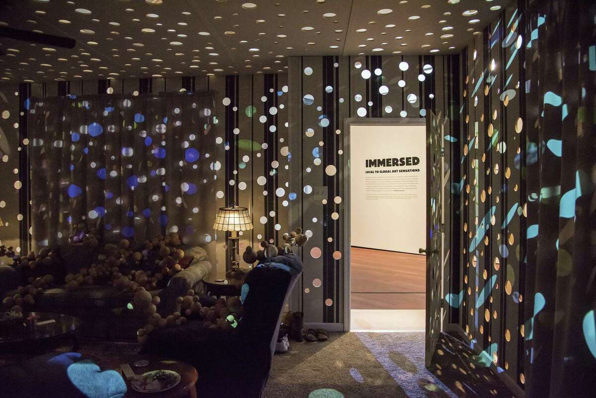 Chris Sauter's “Pleasure Principle” features a modern living room filled with light from video projections that filter through holes.