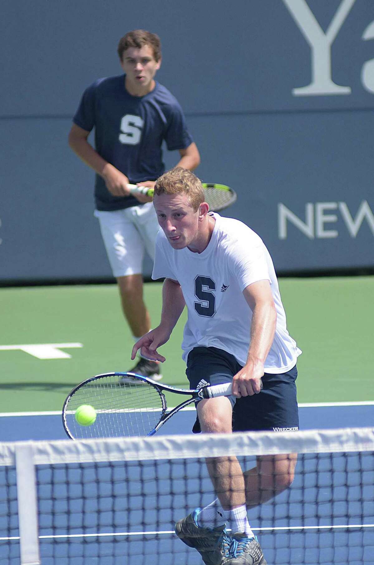 Staples’ Eric Greenberg, bottom, hits a volley over the net as teammate Jack Tooker looks on during Wednesday’s State Open boys tennis doubles championship match against Norwalk at the Connecticut Tennis Center in New Haven.