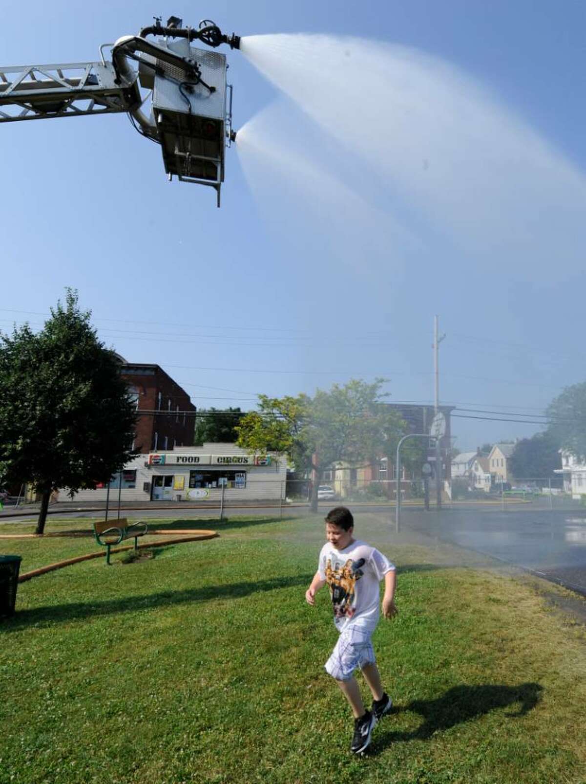 Michael Nash, age 10, runs through the spray from a Troy Fire Department reserve Ladder-Tower in the park on 112th Street in Troy, Tuesday morning. (Skip Dickstein/Times Union)