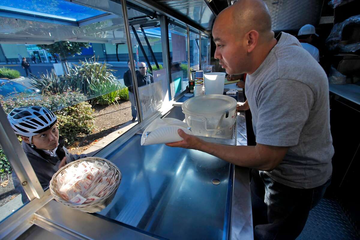Jose Castellanos from the El Tonayense Taco Truck serves a burrito to a customer, Monday Nov 8, 2010, in San Francisco, Calif.