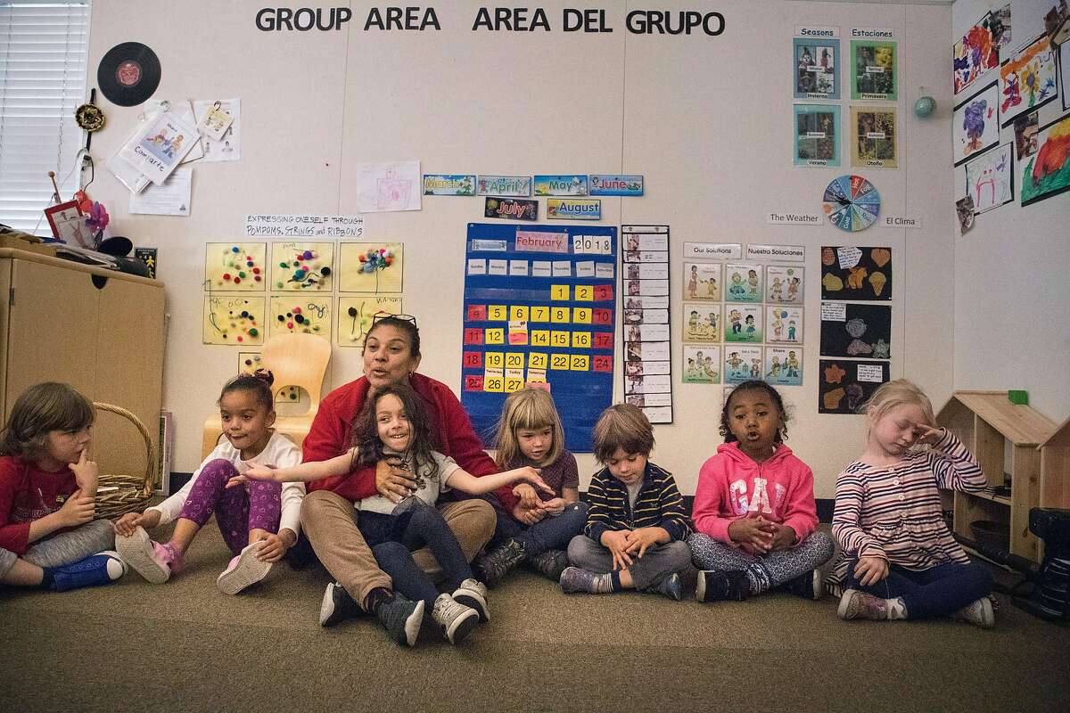 Five-year-olds, Elisa Gibson, Jazlynn Padilla, Nova Lucas, Griffin Ells-Kingsbury, Layla Landry and Sadie Scarlett in a circle play with teacher Betty Lopez at the Holy Family Day Home on Tuesday, Feb. 27, 2018 in San Francisco, CA. If the child care ballot measure passes, it would help families pay tuition at centers like this one.