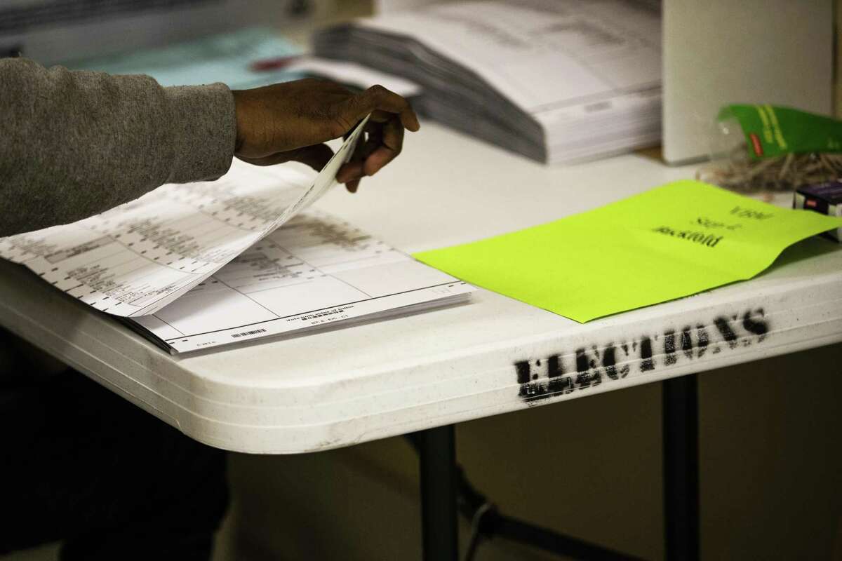 A worker unfolds and flattens ballots at the Department of Elections in San Francisco on Thursday.