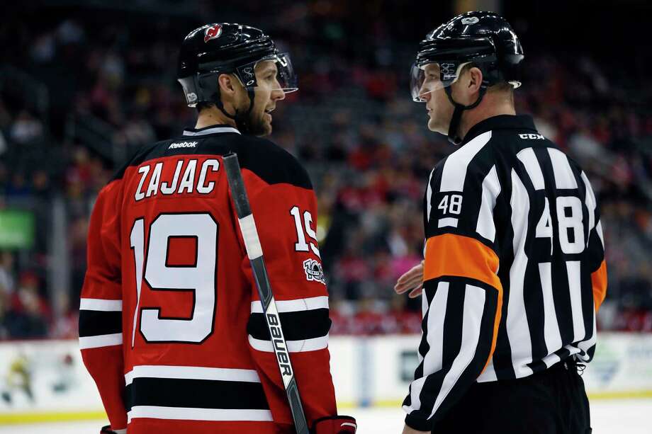 File-This March 28, 2017, file photo shows New Jersey Devils center Travis Zajac, left,  talking to referee Garrett Rank, right, during the first period of an NHL game, in Newark, N.J.  Rank, a full-time NHL referee who played only four rounds of golf during the hockey season, was co-medallist at his qualifying site in Georgia and will play his first U.S. Open this week. Rank, of Elmira, Ont., worked 73 games during the regular season and three playoff games in his second NHL season. But his golf resume is just as impressive. He is a three-time Canadian Mid-Amateur Champion and represented Canada at the Pan-Am Games in 2015. (AP Photo/Julio Cortez, File) Photo: Julio Cortez / Copyright 2017 The Associated Press. All rights reserved.