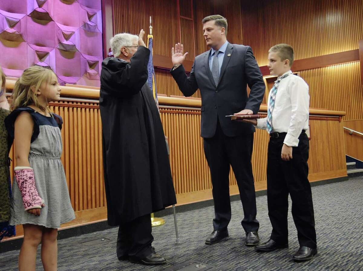 Judge Paul Peter, second from left, swears in Assemblymember Jake Ashby, as Ashby's son, Holden, 10, holds the Bible and his daughter, Elika, 7, looks on during a Assembly Minority Conference swearing-in ceremony for new members on Monday, June 11, 2018, in Albany, N.Y. (Paul Buckowski/Times Union)