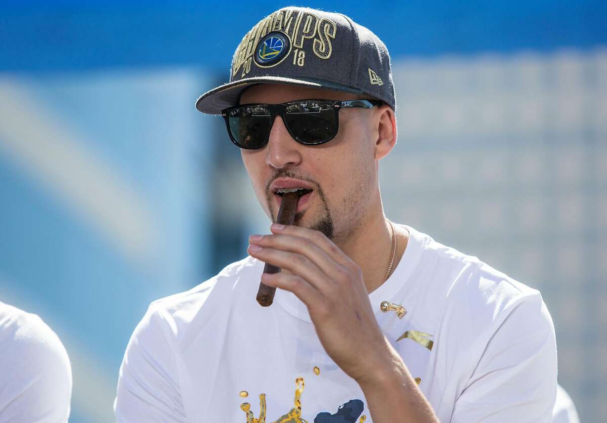 Warriors' Klay Thompson holds a cigar during an NBC Bay Area Sports question and answer session with the team and coaches before the start of the Golden State Warriors NBA Finals victory parade in downtown Oakland, Calif. Tuesday, June 12, 2018.