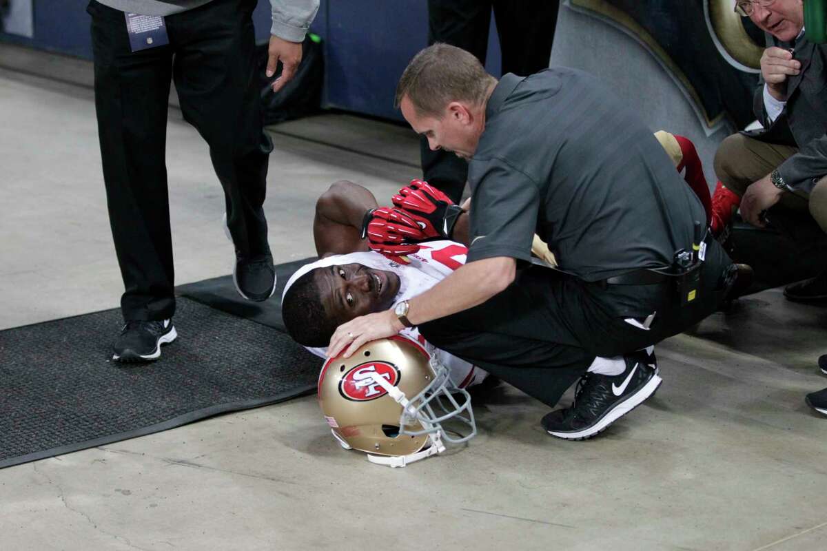 FILE - In this Nov. 1, 2015, file photo, San Francisco 49ers running back Reggie Bush is tended to by a trainer after slipping out of bounds after a running the ball during the first quarter of an NFL football game against the St. Louis Rams, in St. Louis. Former NFL running back Reggie Bush says dangerous conditions at a St. Louis stadium led to a season-ending injury in a case that could leave the city on the hook for damages, even though the Rams are long gone. The St. Louis Post-Dispatch reports that defendants in the civil trial, which began Tuesday, June 5, 2018, include two public entities. (AP Photo/Tom Gannam, File)