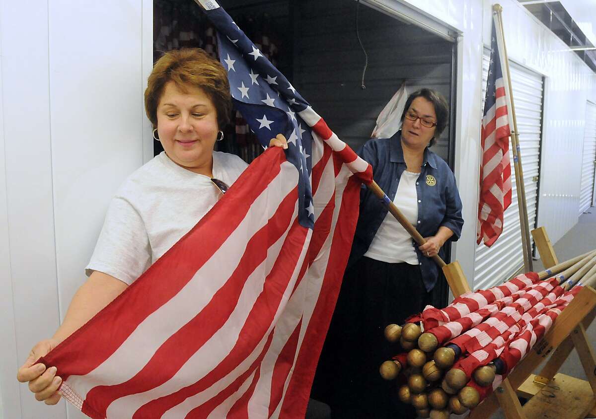 Kngwood Rotary Club members Carolyn Wise and Tommie Buscemi of American Flags examine the American Flags inside their storage unit. The Kingwood Rotary Club places the American Flag at residents and businesses, that have subscribed to the Rotary Club, during certain holidays. Photo by David Hopper