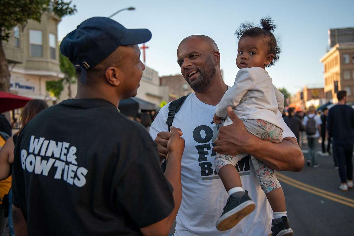 Max Gibson (left) greets his friend Travis Watts and Watts' daughter Zaya Felton, 15 months, while promoting Feels 6 at Oakland's First Friday on Friday, June 1, 2018.
