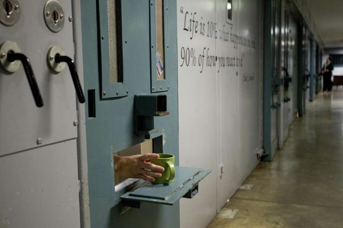 An inmate reaches out for his cup in the administrative segregation wing of the Estelle Unit Wednesday, March 5, 2014, in Huntsville, Texas. During the last six years, Texas prisons have reduced by 25 percent the number of inmates confined to administrative segregation, or solitary confinement. Texas prison officials are following a nationwide movement towards reducing the number of inmates in solitary, especially those who are scheduled to be released. ( Brett Coomer / Houston Chronicle )