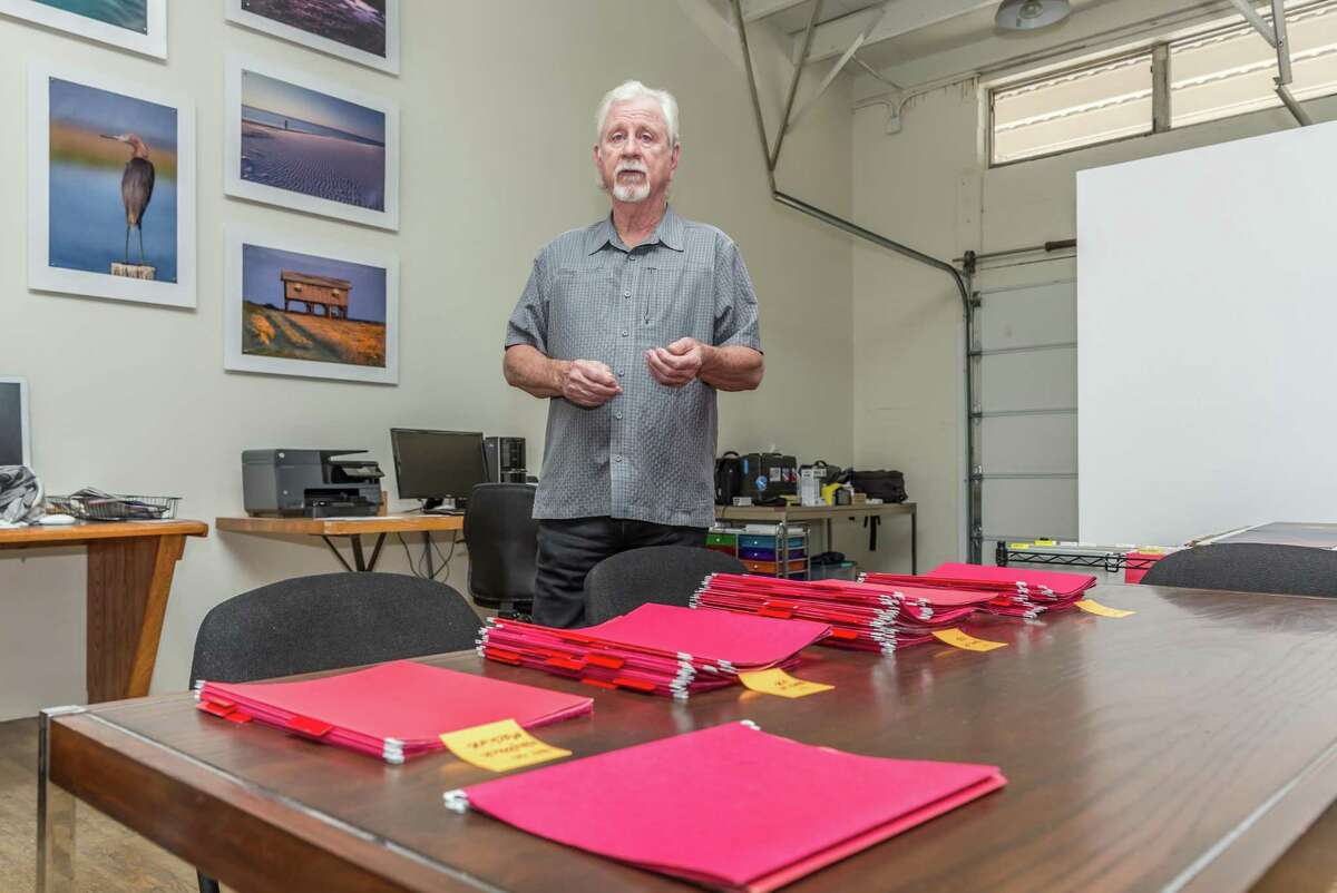 Jim Olive, owner of Stockyard Photos located in Houston, in front of categorized folders that represent images that have been used without license or permission.