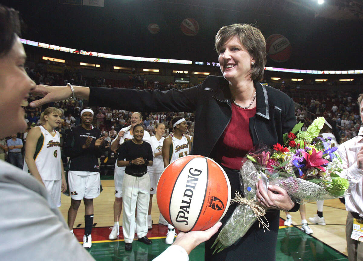 FILE - In this Aug. 19, 2005, file photo, Seattle Storm coach Anne Donovan, right, smiles as she is handed the game ball by team official Karen Bryant following the Storm's victory over the Minnesota Lyn in Seattle. The victory gave Donovan her 100th career WNBA victory as a coach, the first woman to reach that plateau. Donovan died Wednesday, June 13, 2018, of heart failure. She was 56. Donovan's family confirmed the death in a statement. (AP Photo/Elaine Thompson, File)