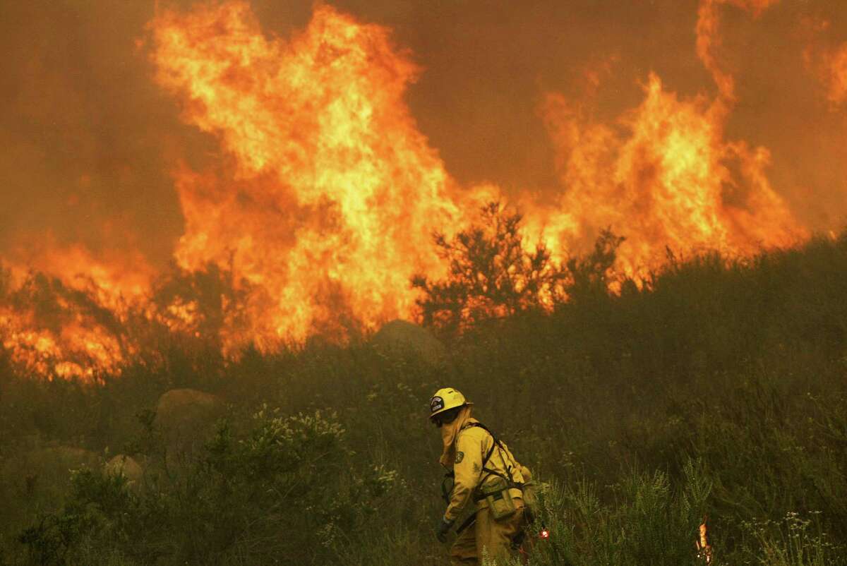 A California Department of Forestry firefighter sets a backfrie to save a home threatened by a wildfires. A group of California cities is suing Exxon Mobil for damages caused climate change, including the possibility of more wildfires.