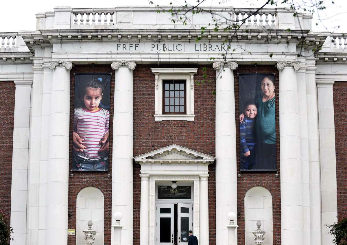 Photographs of immigrants hang in the front of the New Haven Free Public Library.