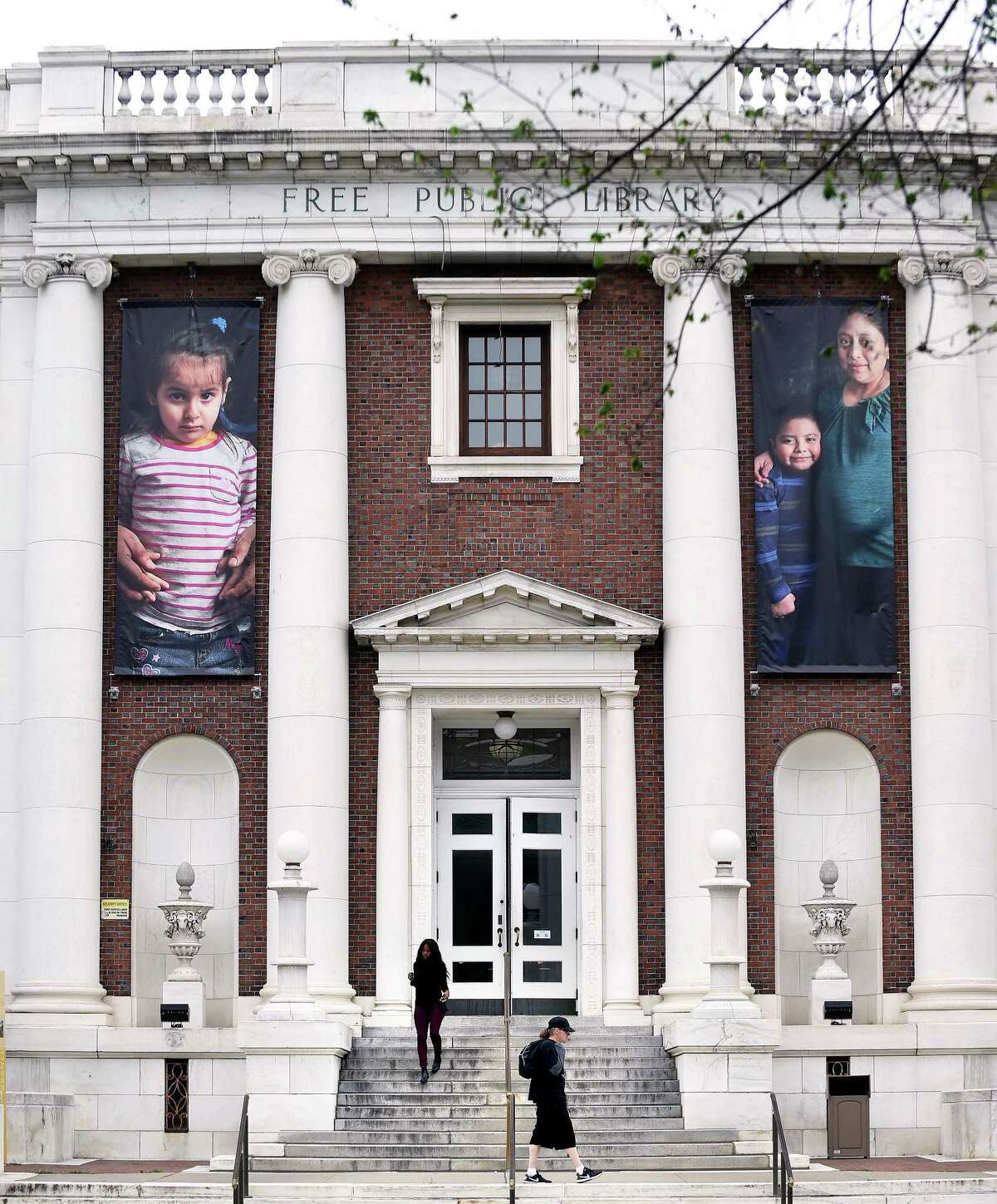 Photographs of immigrants hang in the front of the New Haven Free Public Library.