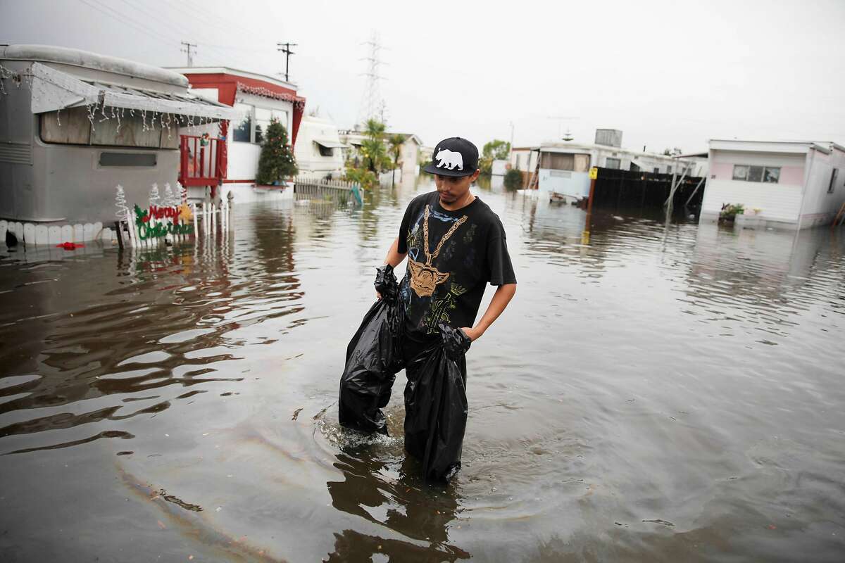 Andres Martinez, R.C. Mobile Park resident, returns to his home after developing a leak in two garbage bags he had fashioned into home made waders while trying to check on his parents home at the flooded R.C. Mobile Park on Friday, December 12, 2014 in Redwood City, Calif.