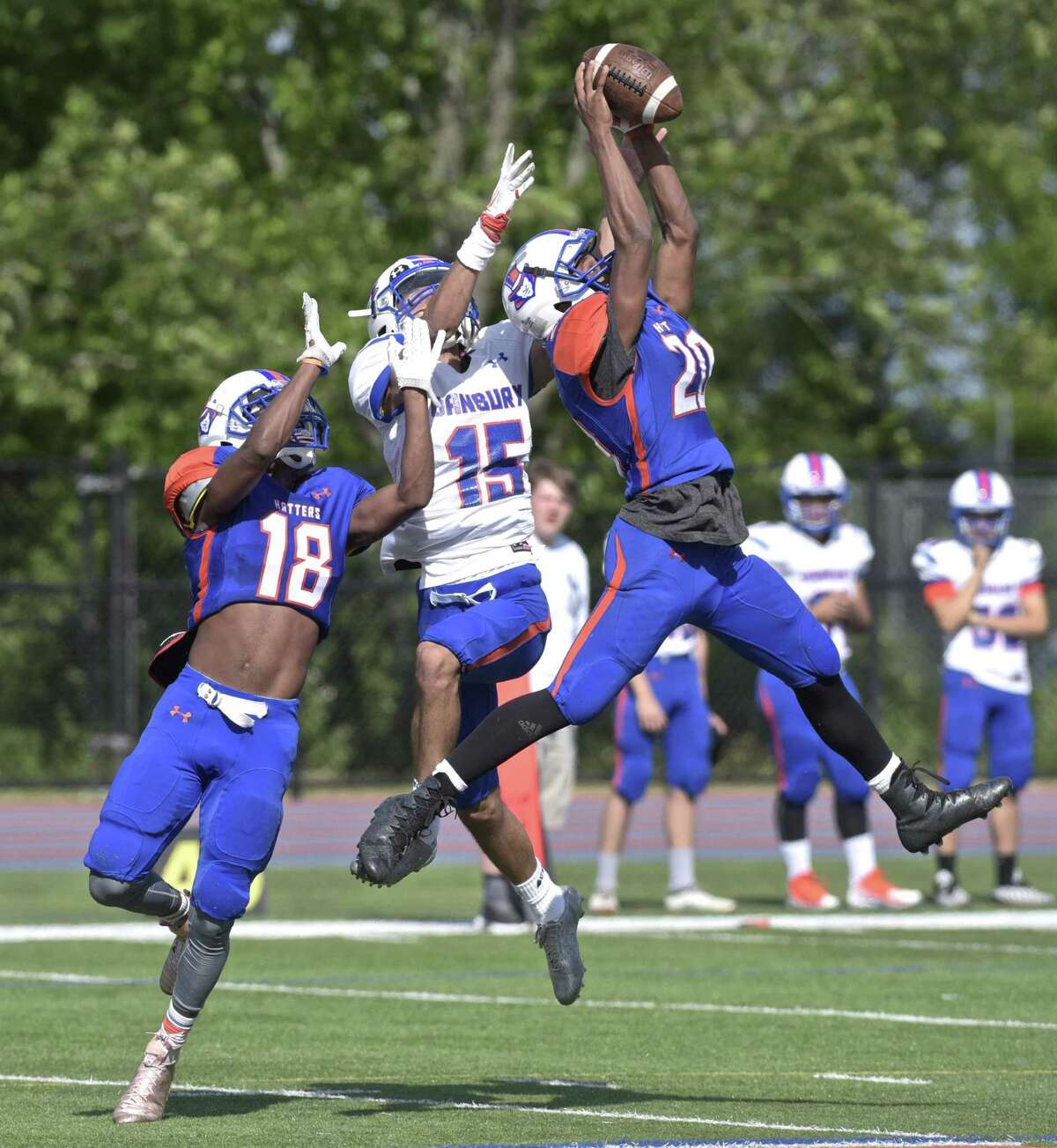 Sylvanus Thompson (20) intercepts a pass intended for Bernie DeLacruz (15), with Ronell Hopkins (18) in on the play, in the annual spring Blue-White Scrimmage of the Danbury High School football team, Friday, June 15, 2018, at Danbury High School, Danbury, Conn.