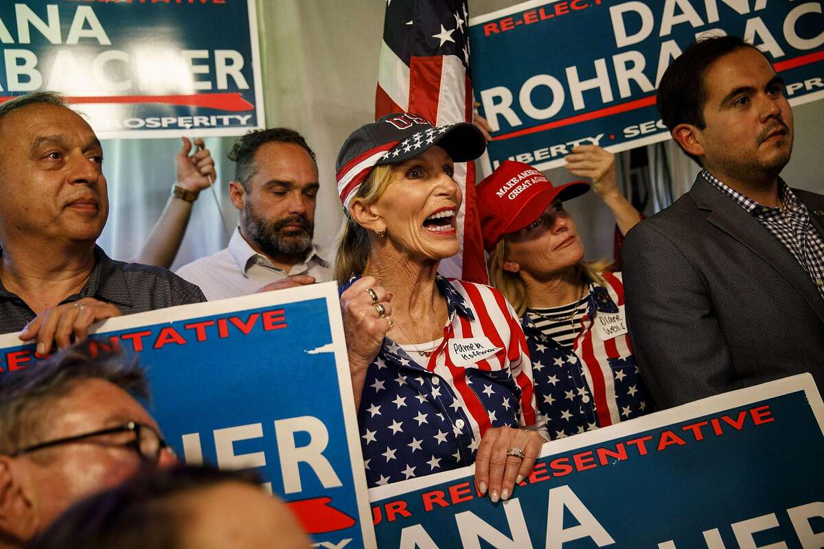 Attendees hold signs and cheer during a primary election watch party for Dana Rohrabacher, Republican U.S. Senate candidate from California, not pictured, in Costa Mesa, California, U.S., on Tuesday, June 5, 2018. California's jungle primary is living up to its name in Orange County, where a former protege of 15-term Rohrabacher is among the names on a crowded June 5 ballot. Photographer: Patrick T. Fallon/Bloomberg