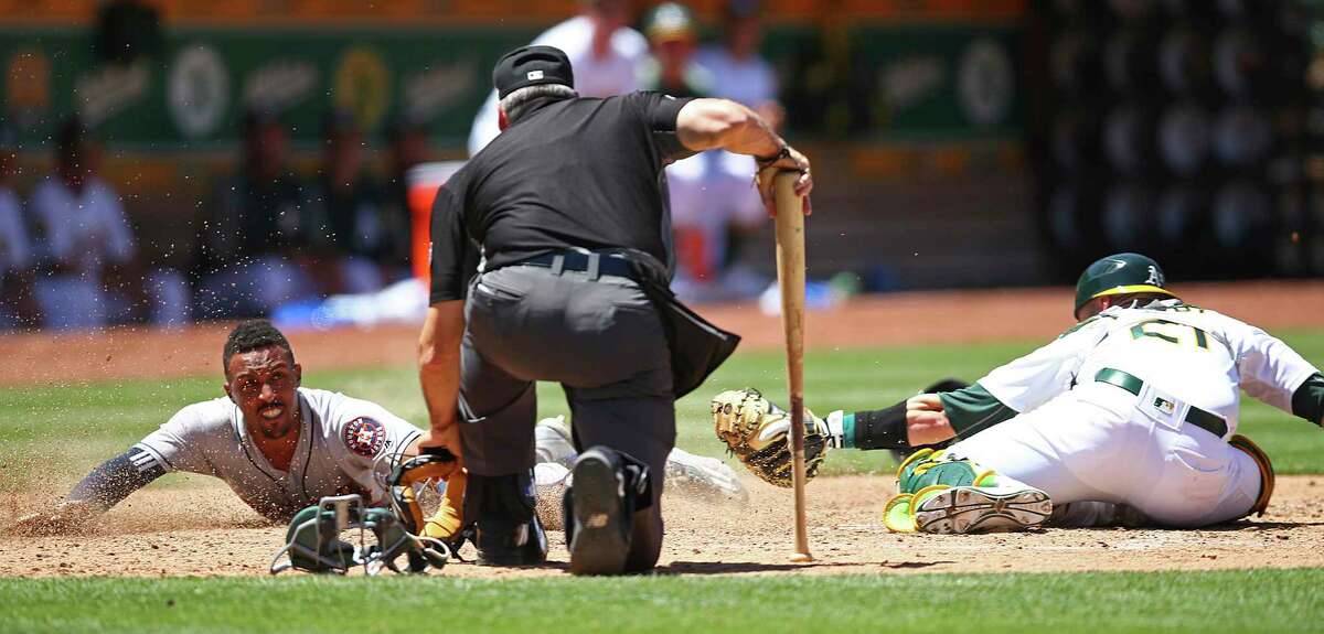 Houston Astros' Tony Kemp, left, scores behind Oakland Athletics catcherJonathan Lucroy in the sixth inning of a baseball game Thursday, June 14, 2018, in Oakland, Calif. Home plate umpire Angel Hernandez, center, watches. (AP Photo/Ben Margot)