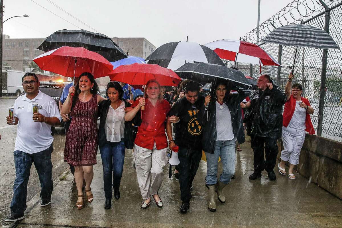 Texas senator Sylvia Garcia, center, links arms with protesters as they march through the rain during a Families Belong Together prayer vigil outside a facility near downtown Houston that has been leased to house unaccompanied immigrant children Sunday, June 17, 2018. (Michael Ciaglo / Houston Chronicle)