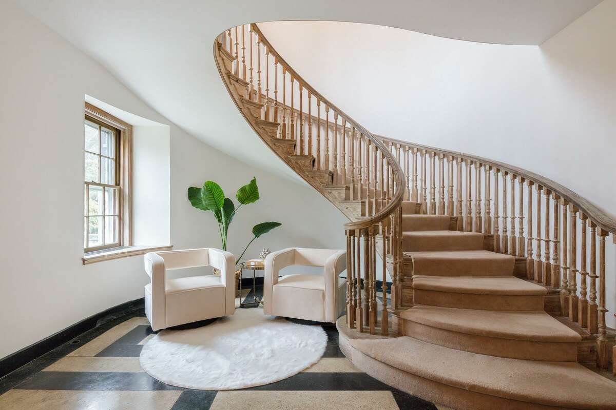 The sizable foyer features a graceful elliptical staircase, wood tile flooring, and a reception room and a powder room.