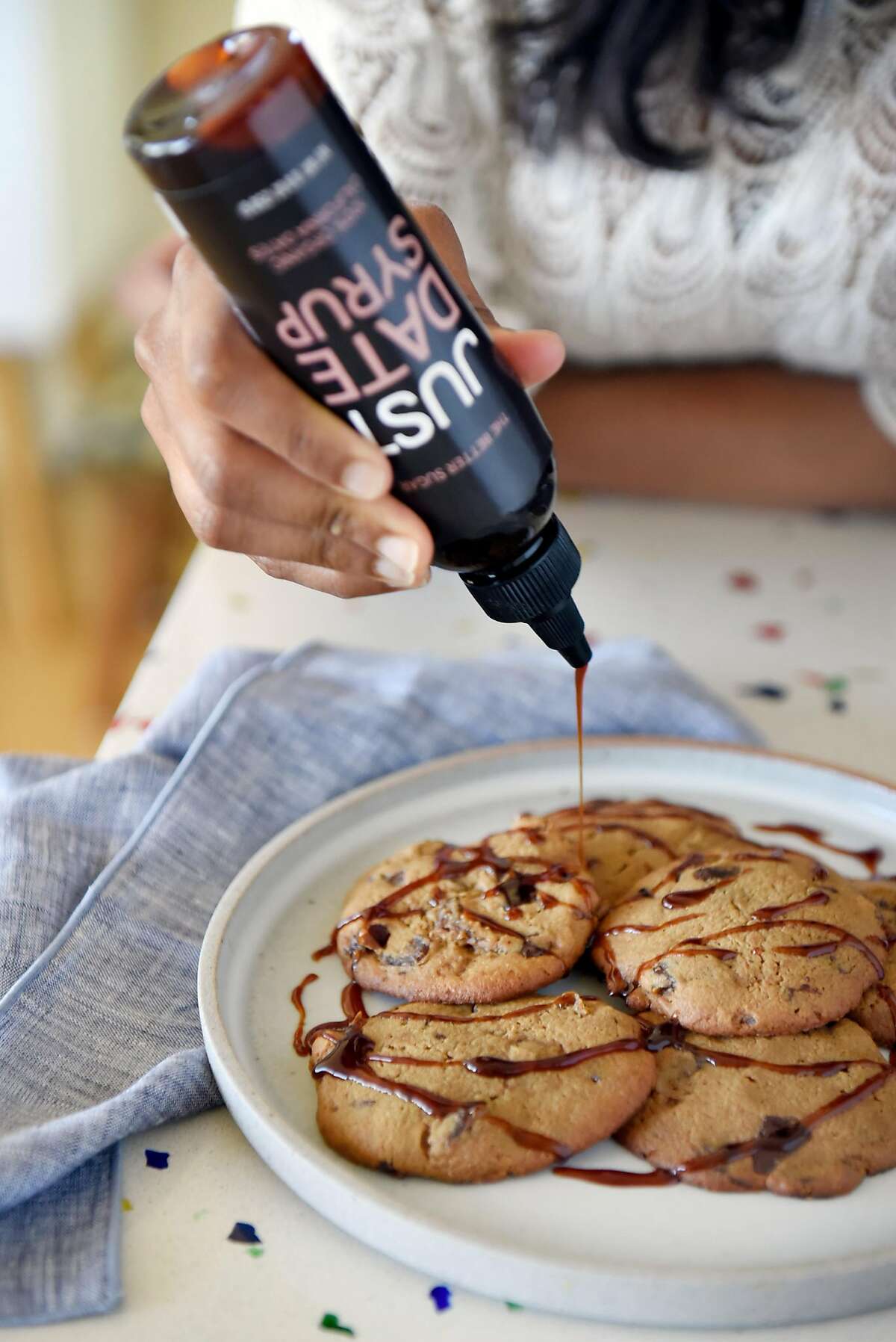 Sylvie Charles drizzles Just Date Syrup on top of a fresh batch of her tahini-date chocolate chip cookies at her home in San Francisco, Calif., on Tuesday June 12, 2018.