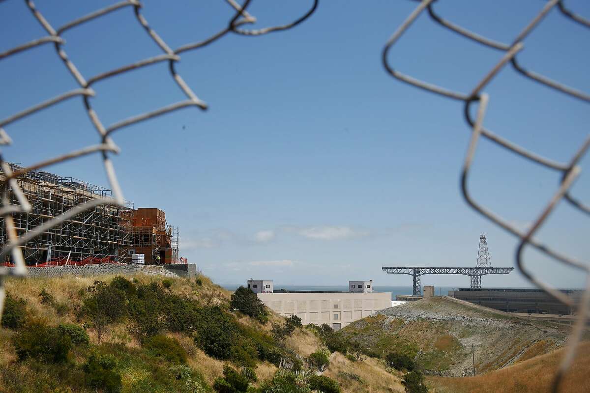 New construction on Parcel A (l to r) next to structures at Hunter's Point Shipyard are seen through a hole in a fence on Thursday, May 17, 2018 in San Francisco, Calif. The California Public Health department will be testing Parcel A for hazardous materials after a botched cleanup on one of the parcels nearby.